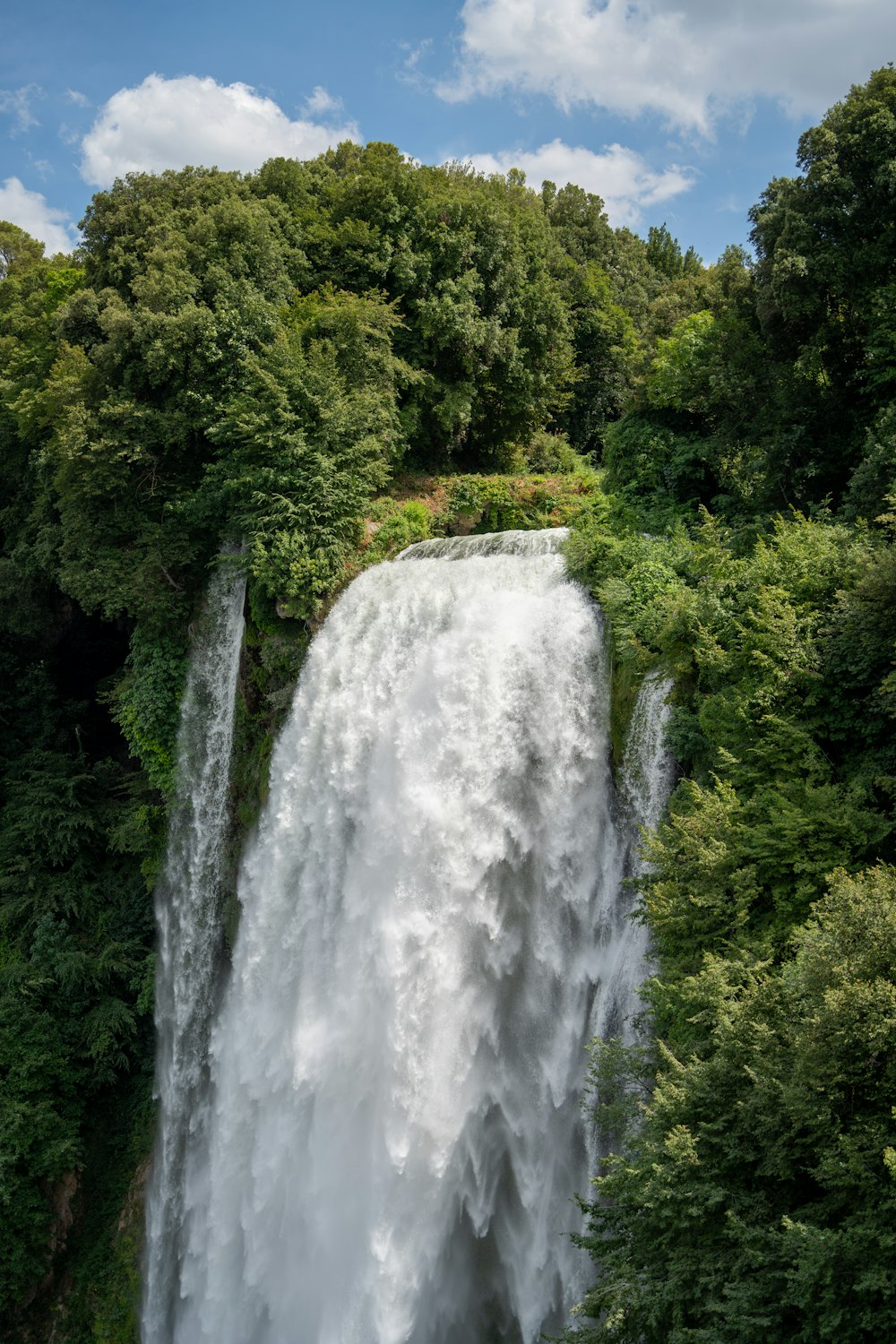 a large waterfall surrounded by lush green trees