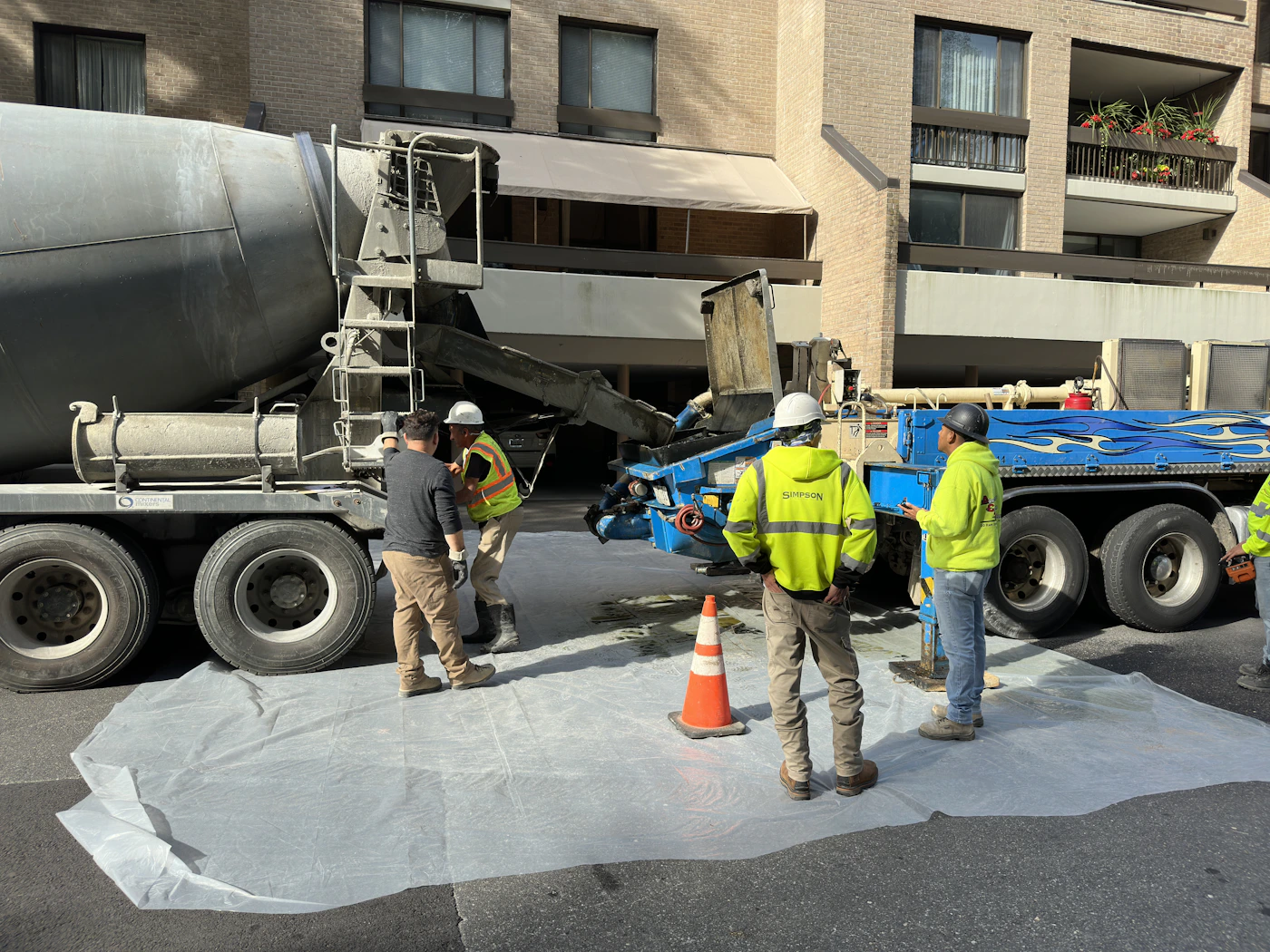 Concrete delivery workers next to a cement truck at an active jobsite