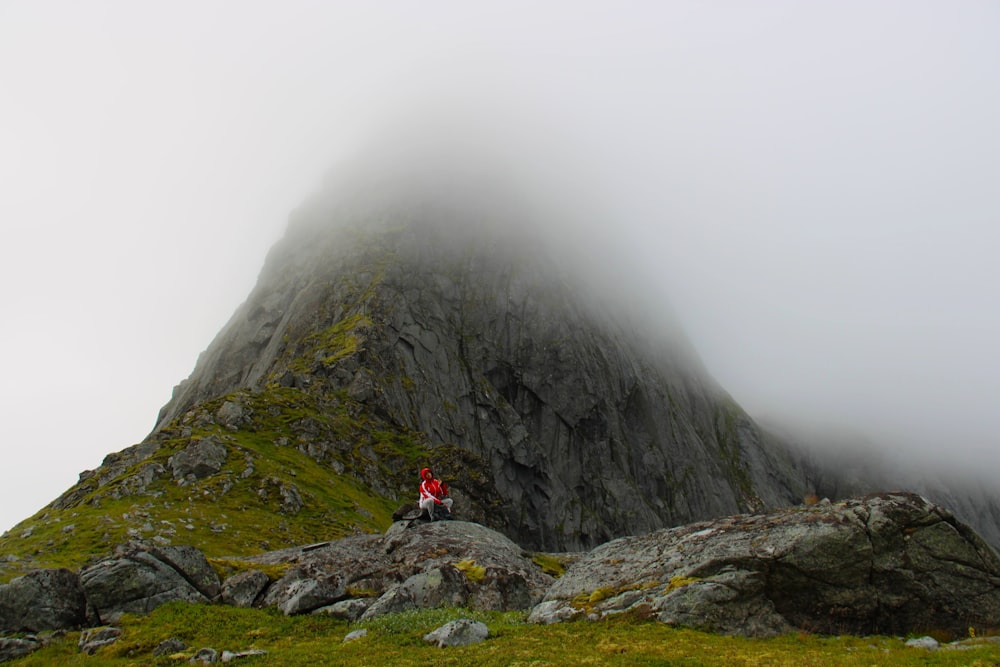 a person sitting on top of a large rock