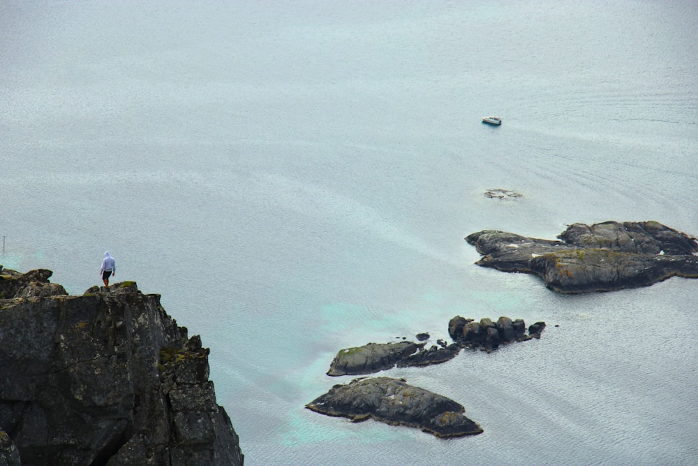 a person standing on top of a cliff near a body of water