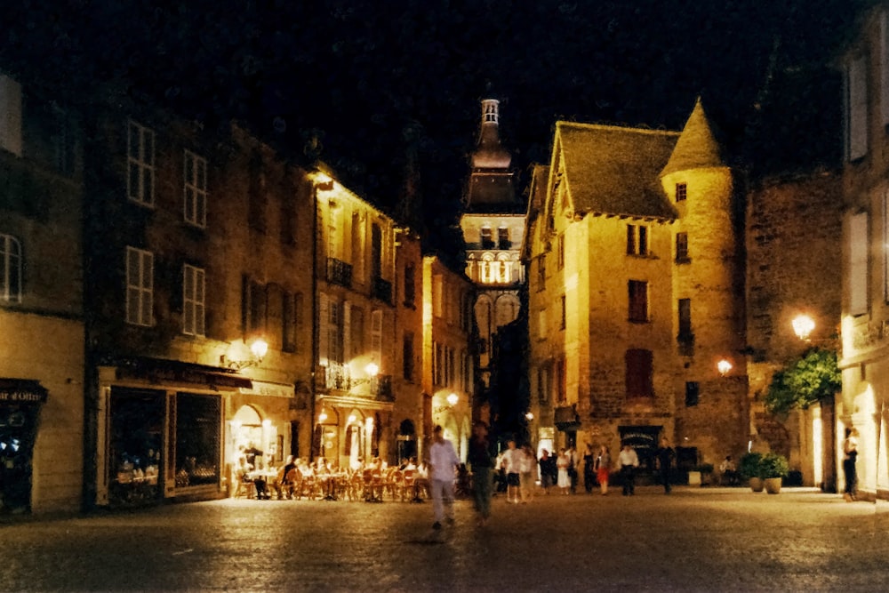 a group of people walking down a street at night