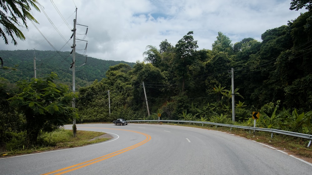 a car driving down a curvy road surrounded by trees