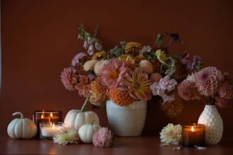 a vase filled with lots of flowers next to candles