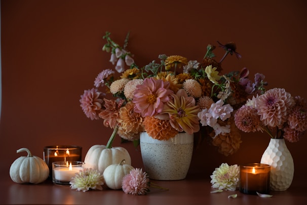 a vase filled with lots of flowers next to candles