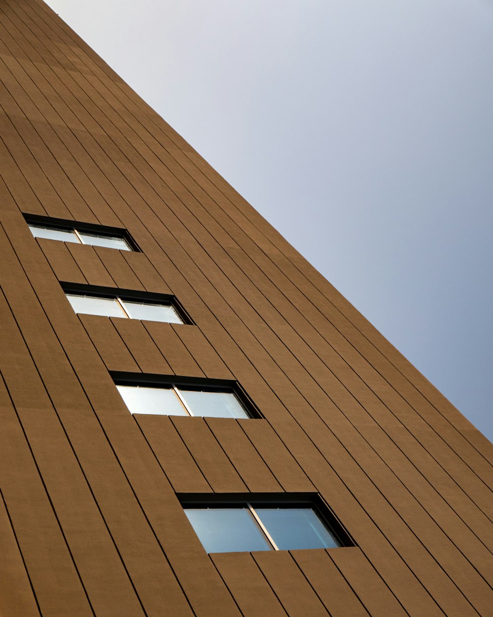 a tall building with three windows and a sky background