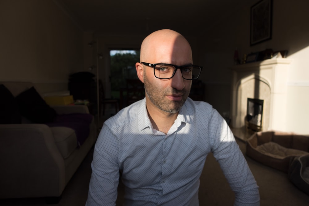 a bald man wearing glasses in a living room
