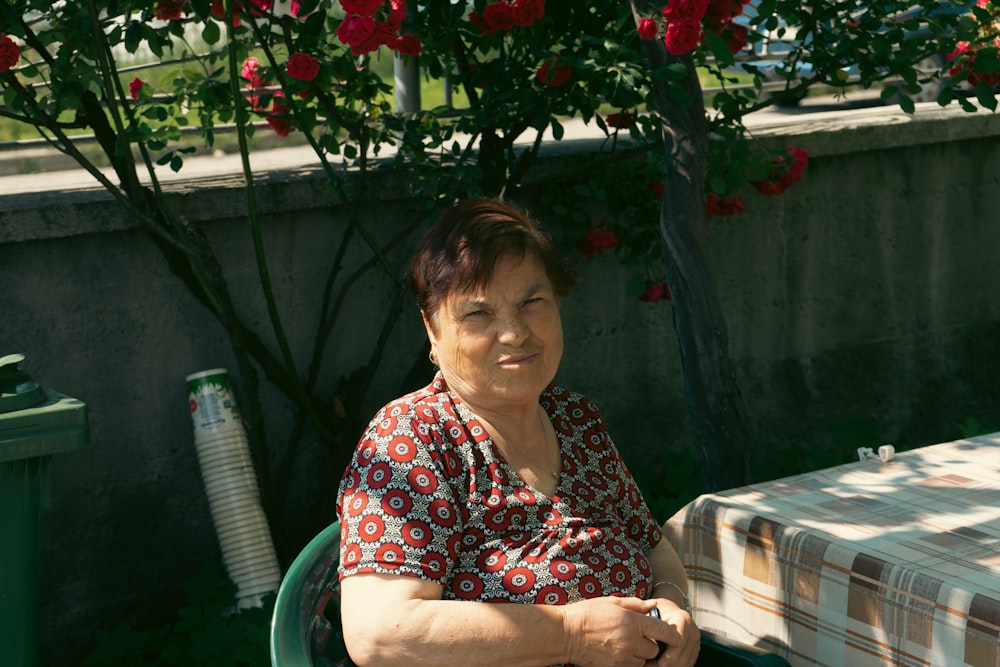 a woman sitting at a table with a flowered tree in the background