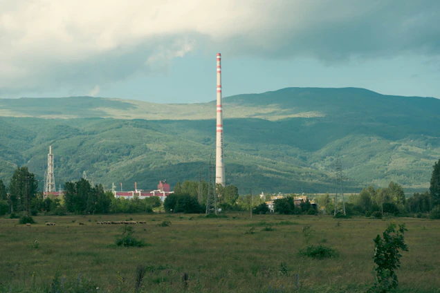 Modern eco-friendly charcoal kiln surrounded by green fields under a clear sky.