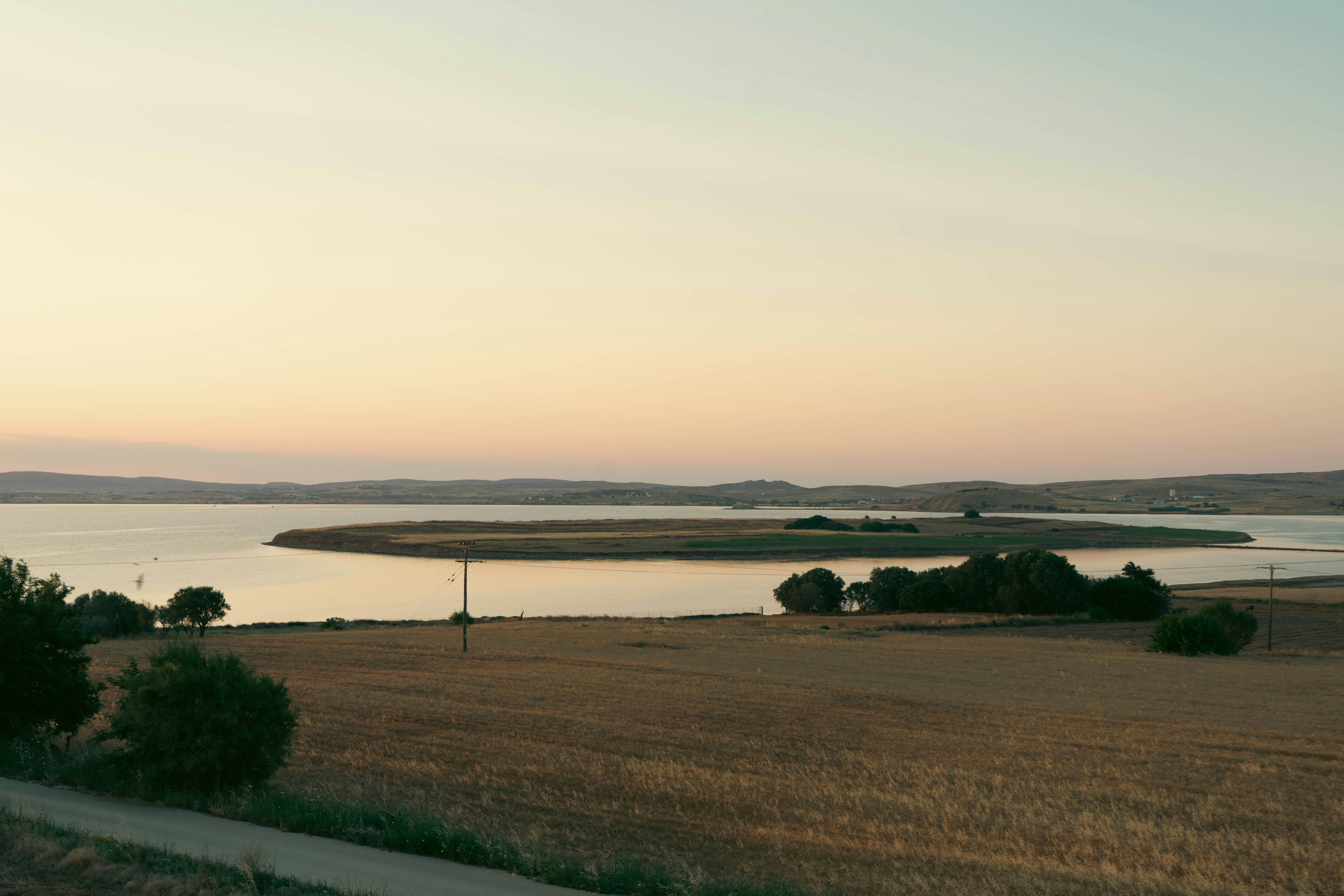 a large body of water sitting next to a lush green field