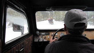 Car driving through snowy road with visible sensor equipment on the hood.