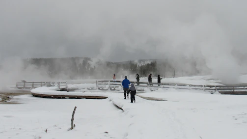 A serene Icelandic landscape with travelers walking calmly on a snowy trail under soft pastel skies.