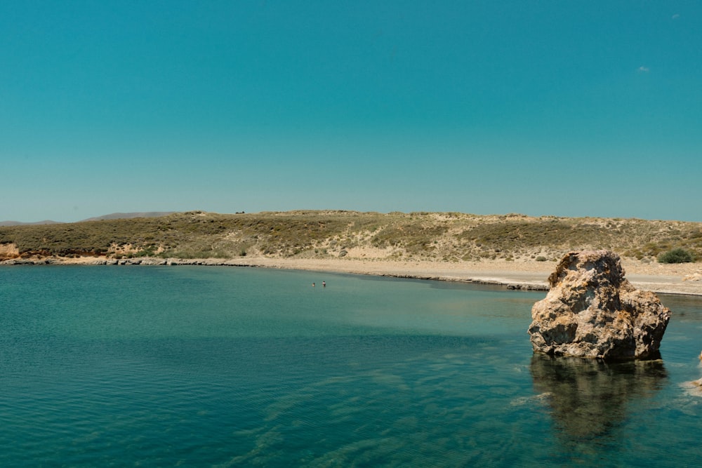 a body of water with a large rock sticking out of it