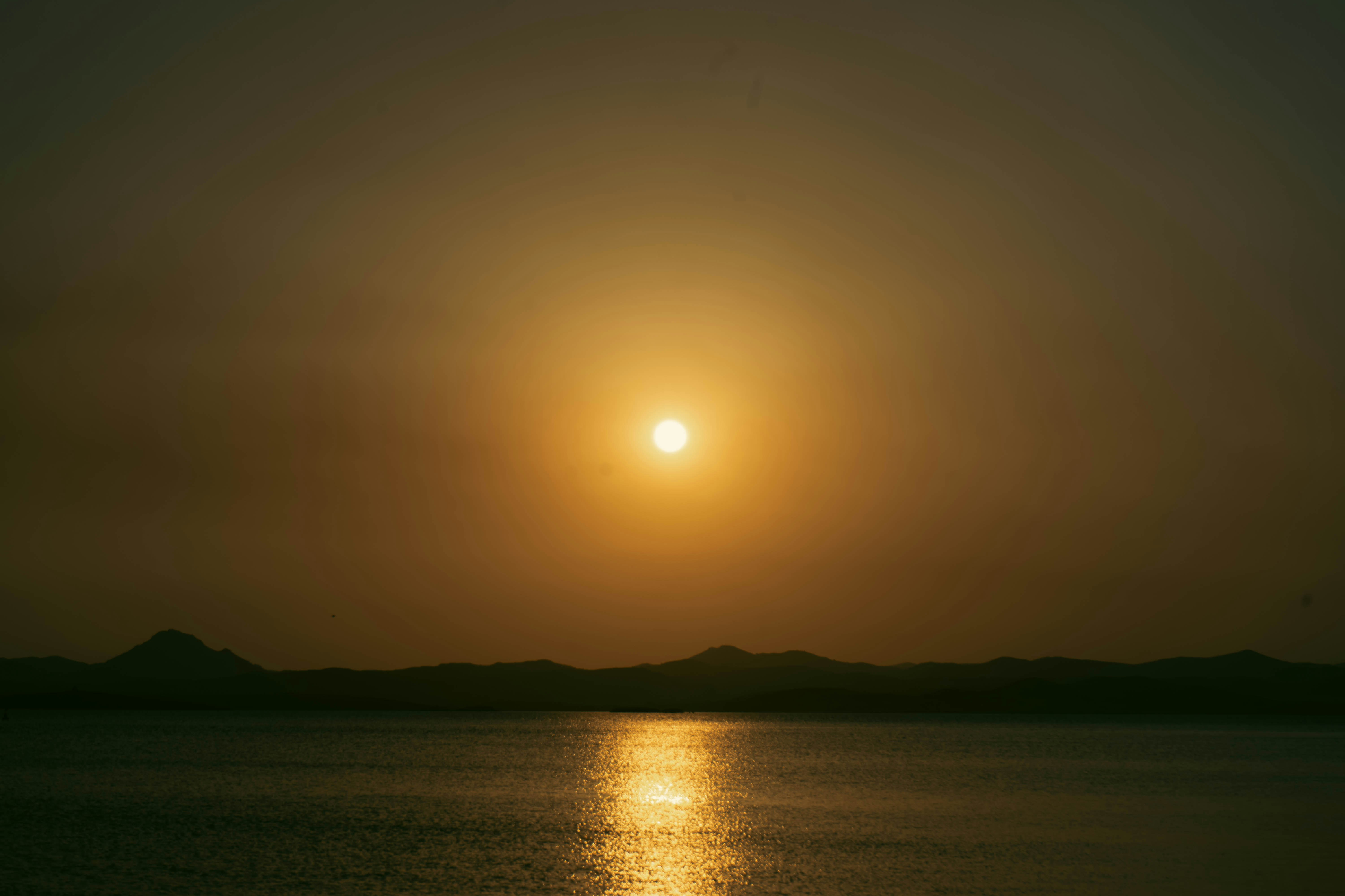 a large body of water with a sunset in the background