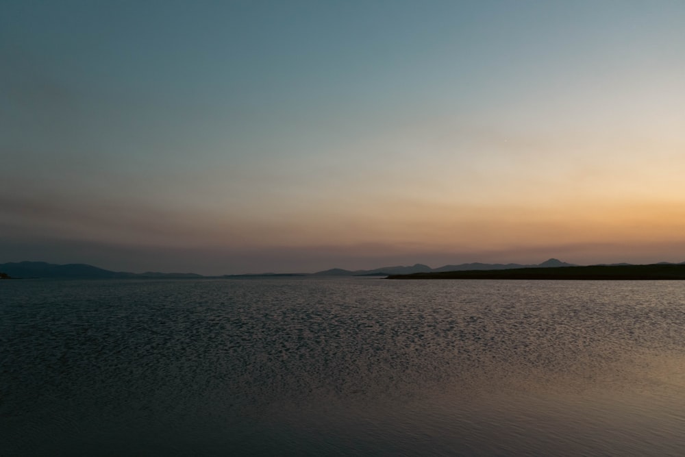 a large body of water with a sunset in the background