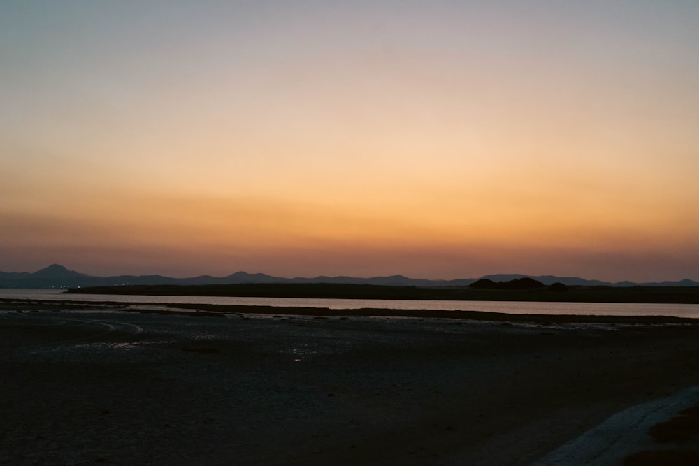 a sunset over a body of water with mountains in the background