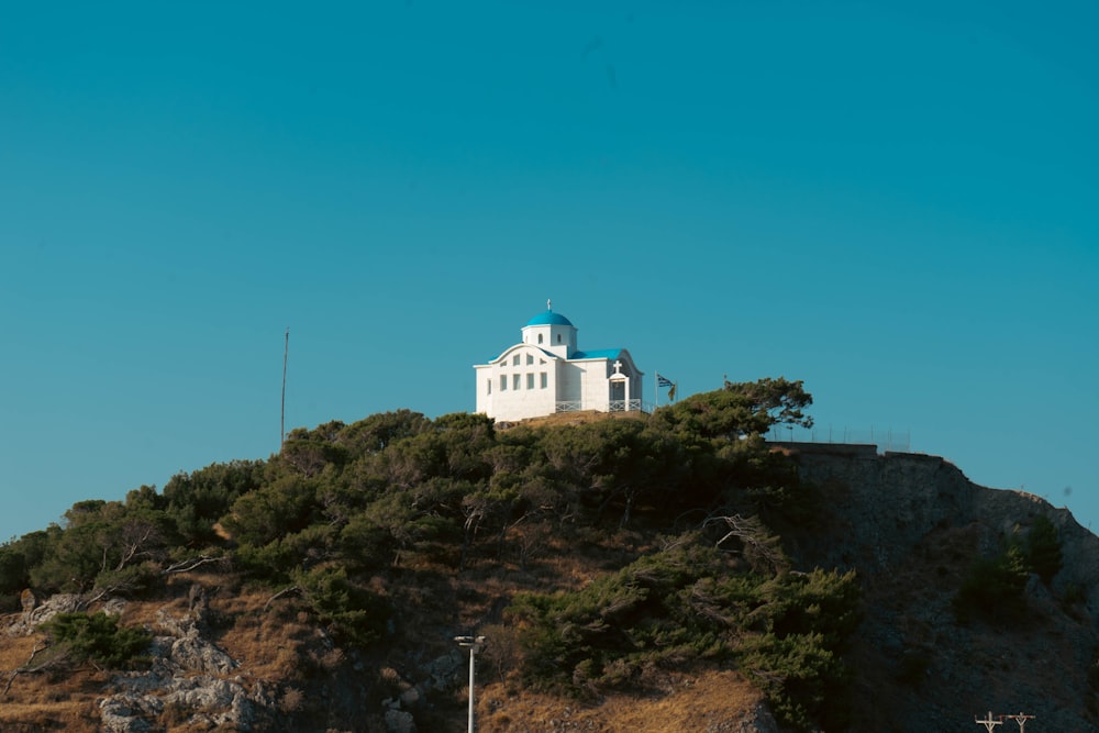 a white church on a hill with a blue sky in the background