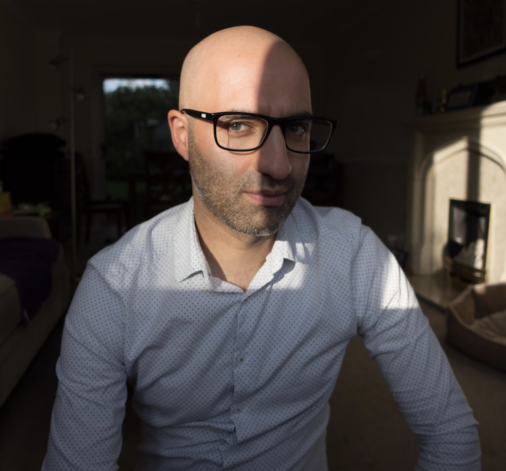 a bald man wearing glasses in a living room
