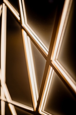 Warm amber light beams intersecting in a delicate geometric pattern.