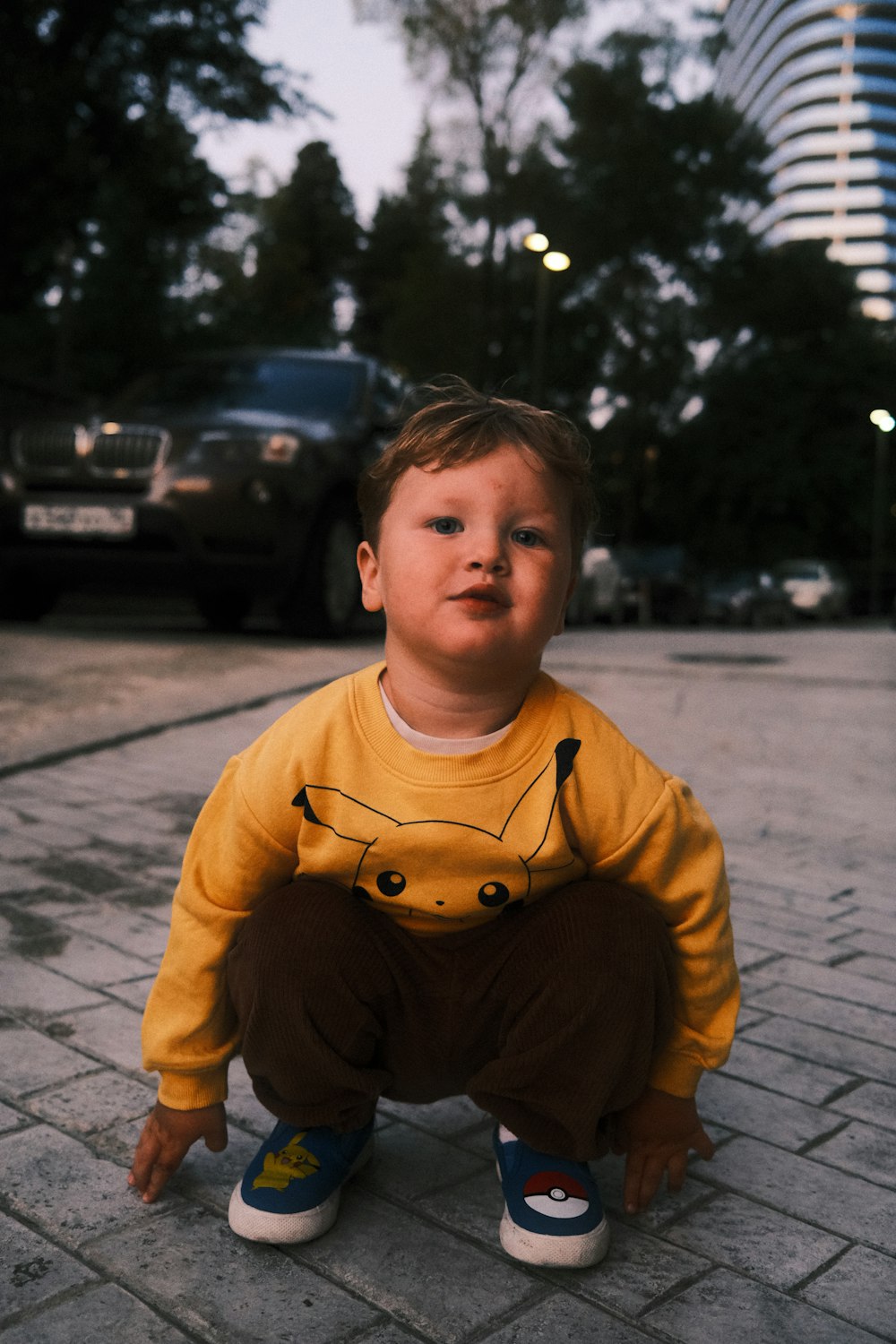 a little boy sitting on the ground in a yellow shirt