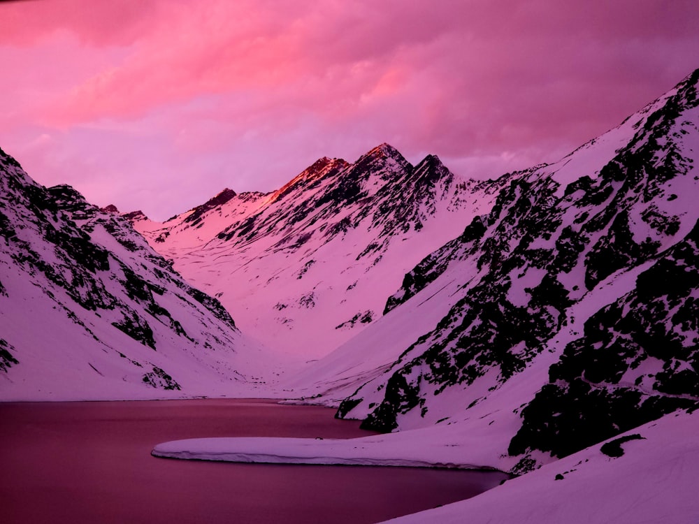 a snowy mountain range with a lake in the foreground