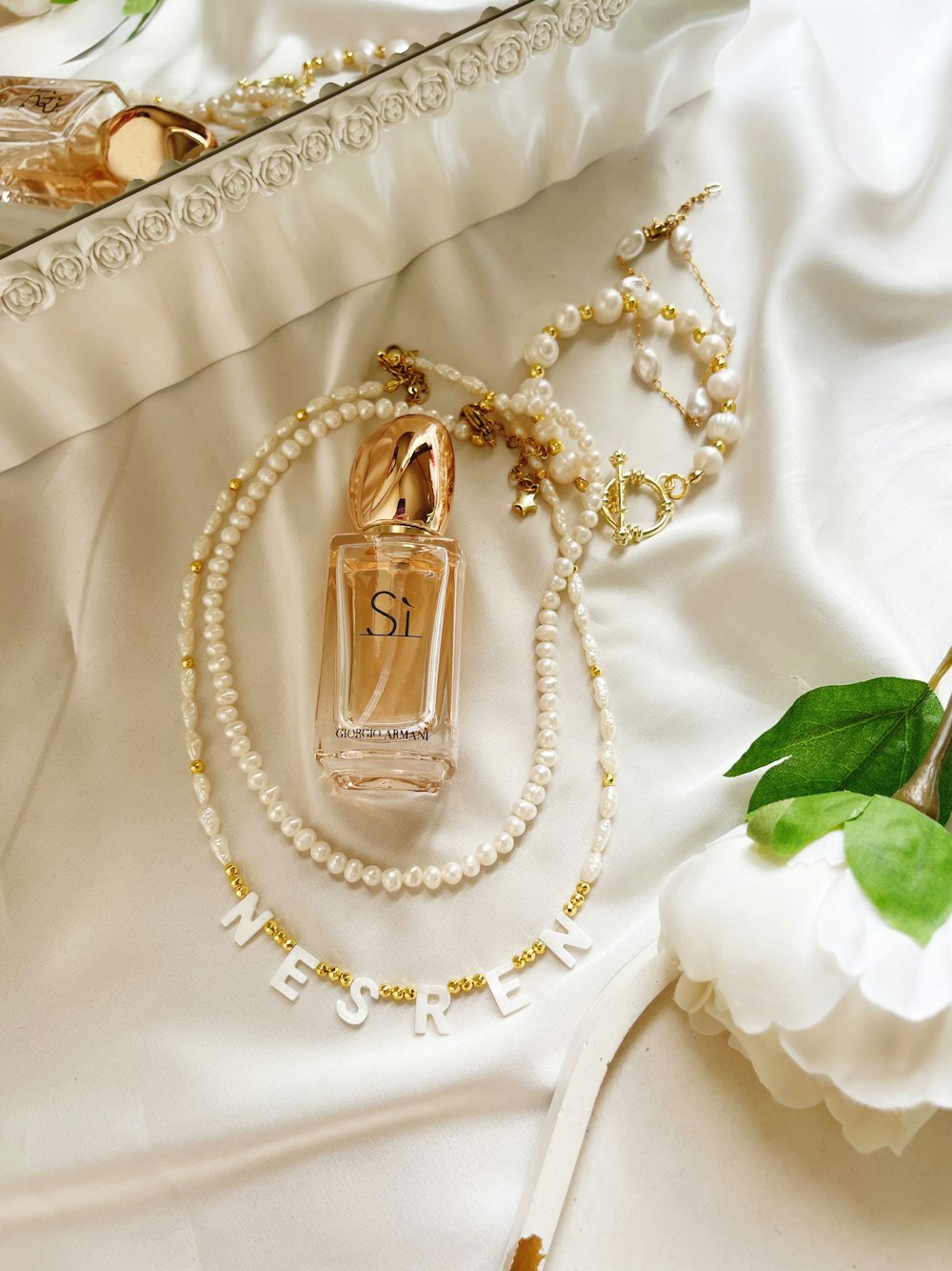 a necklace with pearls and a bottle of perfume