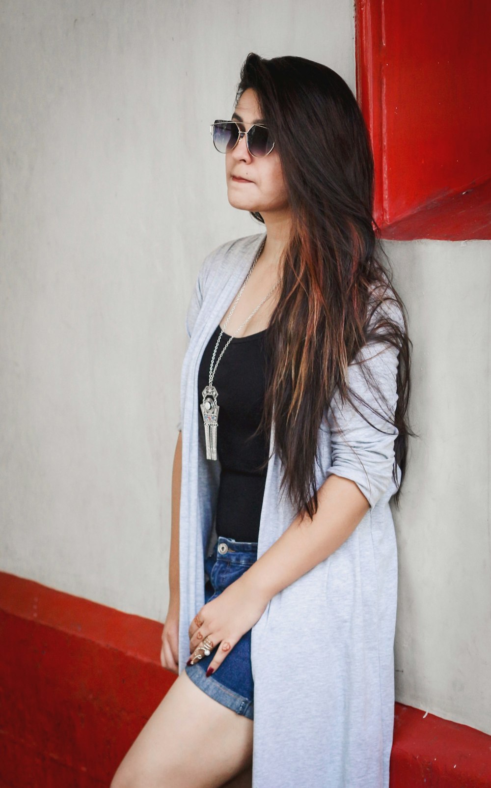 a woman leaning against a wall wearing sunglasses