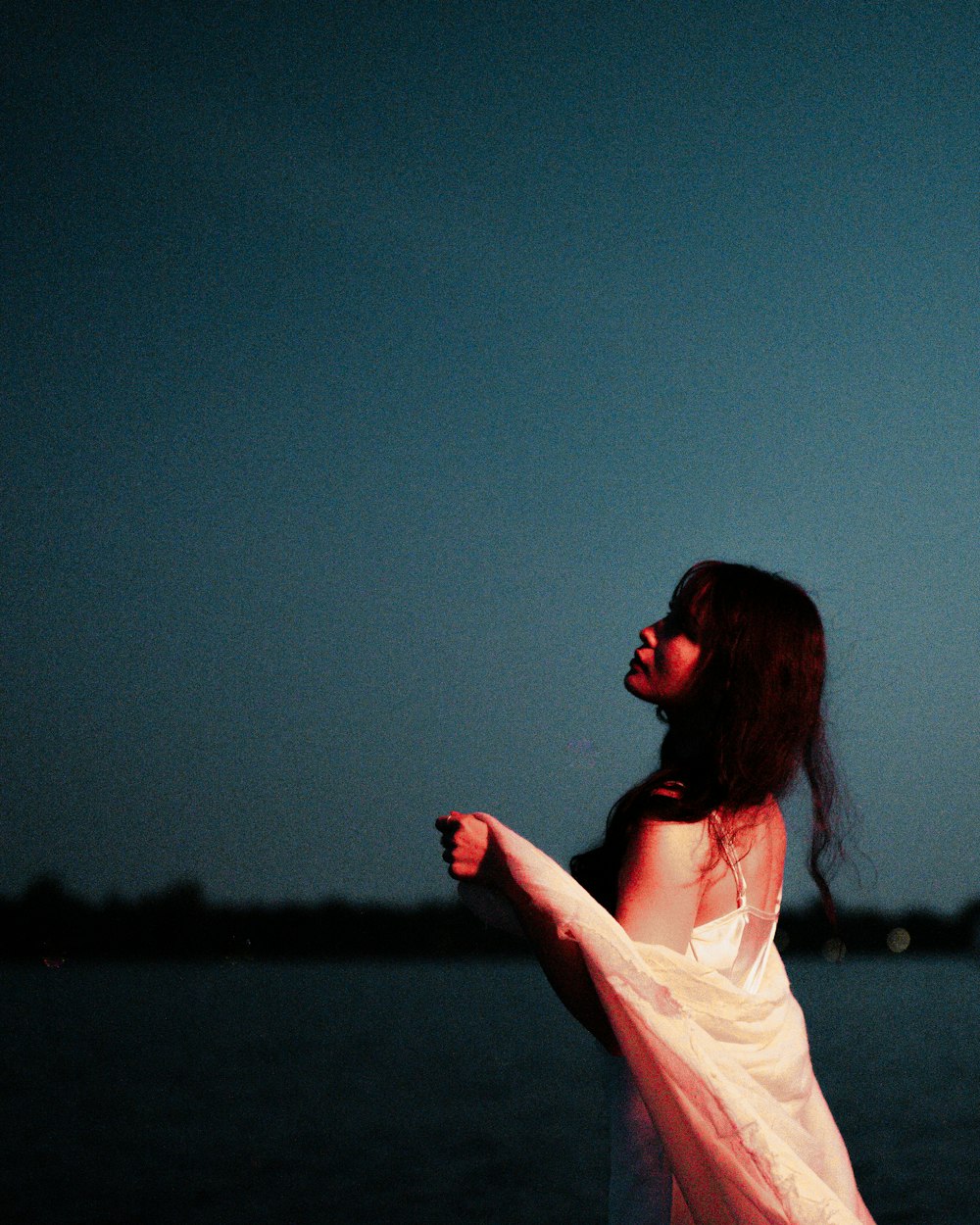 a woman in a white dress is standing by the water