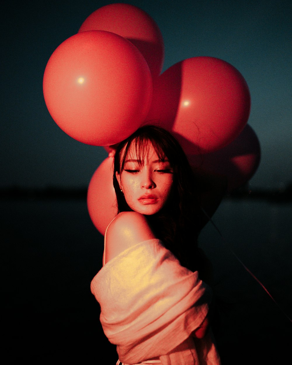 a woman holding a bunch of red balloons