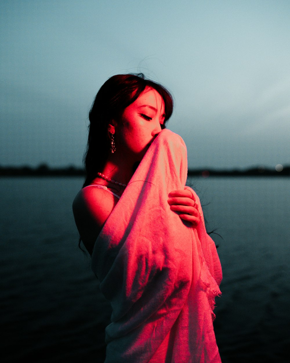 a woman wrapped in a towel by a body of water