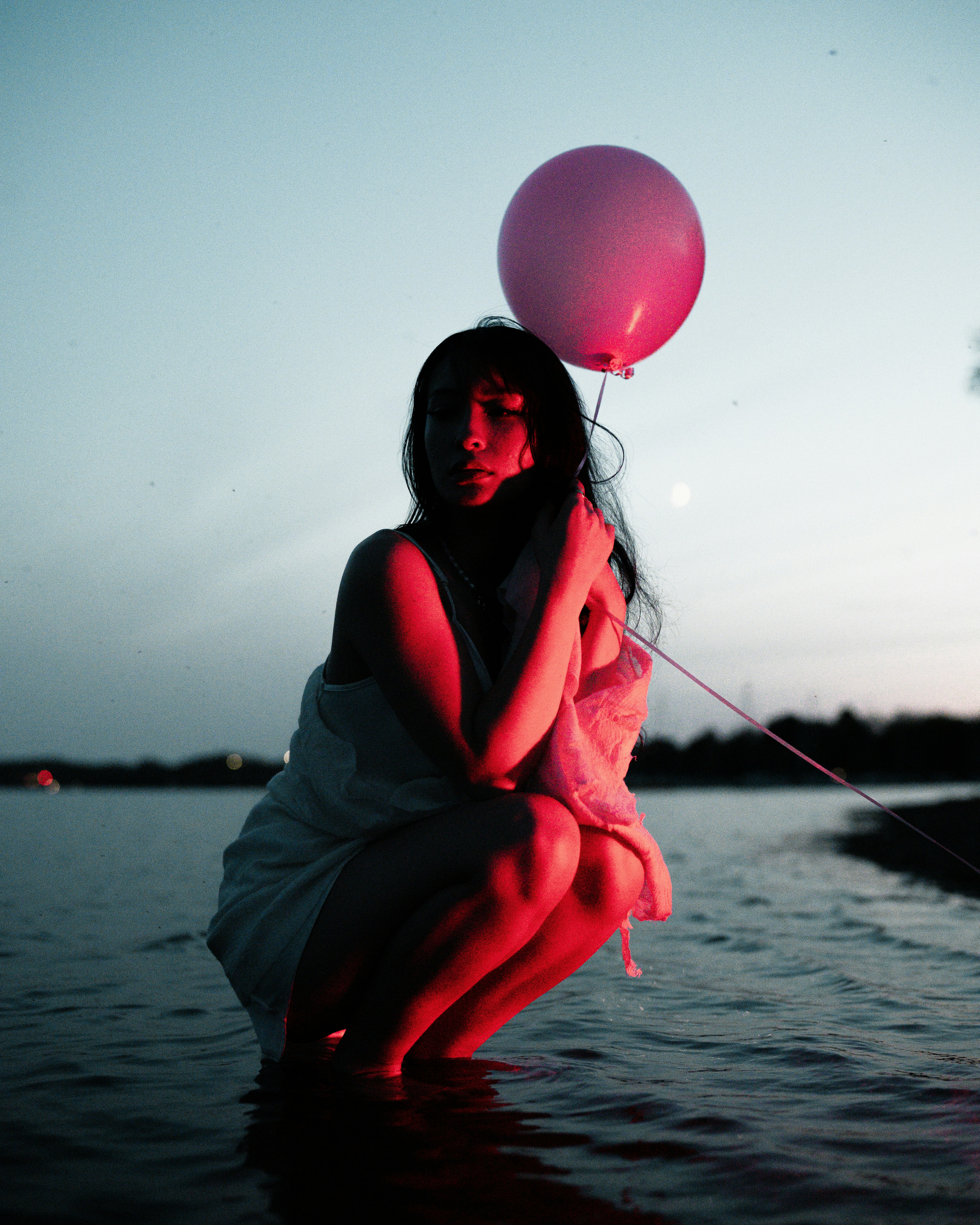 a woman in a white dress holding a pink balloon