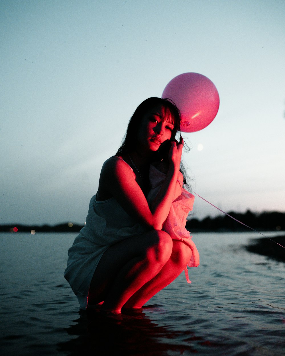 a woman in a white dress holding a pink balloon