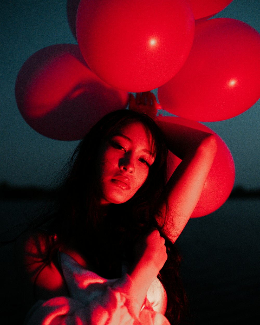 Una mujer sosteniendo un montón de globos rojos