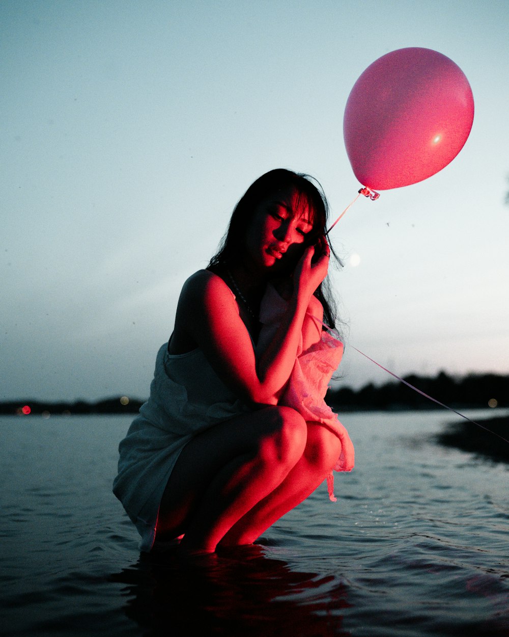 a woman in a white dress holding a pink balloon