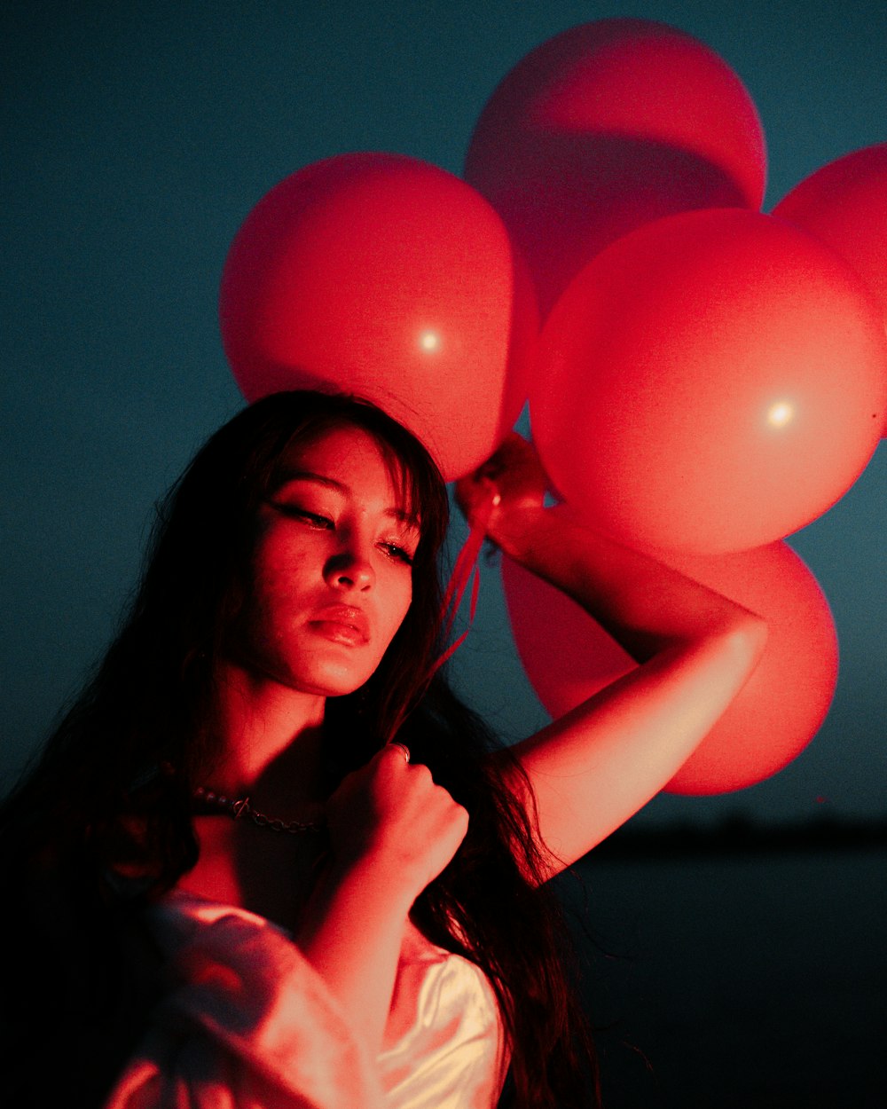 a woman holding a bunch of red balloons