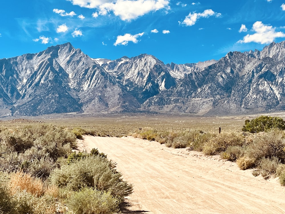 a dirt road in front of a mountain range