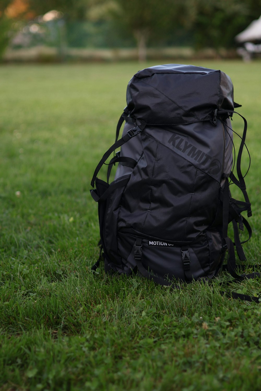 a black backpack sitting on top of a lush green field