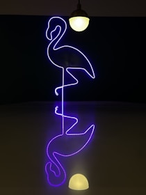 A wrist tattoo featuring a neon pink and orange flamingo with glowing accents.