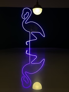 A wrist tattoo featuring a neon pink and orange flamingo with glowing accents.