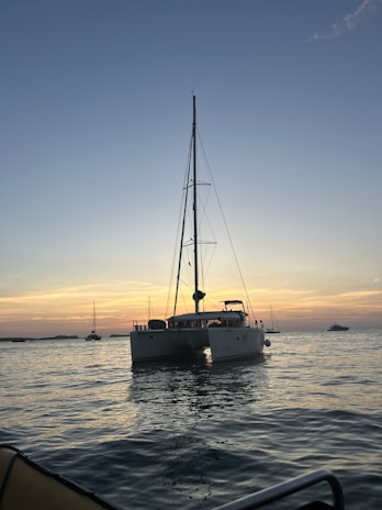 A scenic view of a catamaran sailing on crystal clear waters under a vibrant sunset.