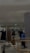 A modern, well-lit clothing store interior featuring several racks of hanging garments, including dresses and coats. The store has a minimalist design with neutral walls and a sleek tile floor. A central display holds a black high-heeled boot, adding a stylish touch. Mirrors are strategically placed to enhance the spacious feel.