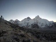 A panoramic view of the Himalayas with a lone trekker on a trail.