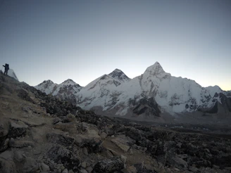A panoramic view of the Himalayas with a lone trekker on a trail.