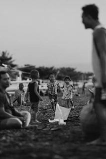 Archival image of children playing near fishing nets on the shore, evoking community life by the sea.