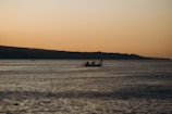 Sunset hues reflecting on calm waters as a boat glides during a peaceful evening fishing trip.