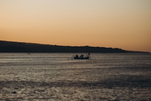 Sunset hues reflecting on calm waters as a boat glides during a peaceful evening fishing trip.