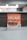 A promotional sign displaying a burger with layers of lettuce, tomato, and beef patty. The sign features the word 'Decade' in bold letters, promoting a contest with a QR code for participation. The background is softly blurred, highlighting the sign as the main focus.