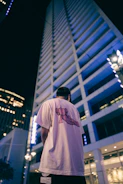 Model wearing a white t-shirt with a striking architectural print, posing against an urban backdrop.