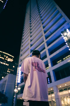 Model wearing a white t-shirt with a striking architectural print, posing against an urban backdrop.