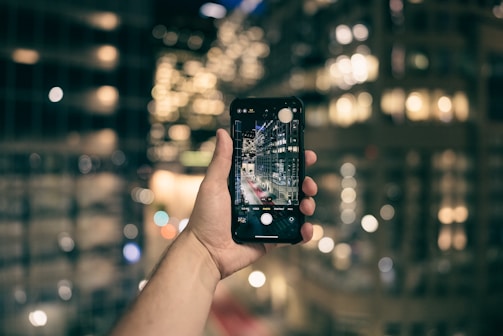 a person taking a picture of a city at night