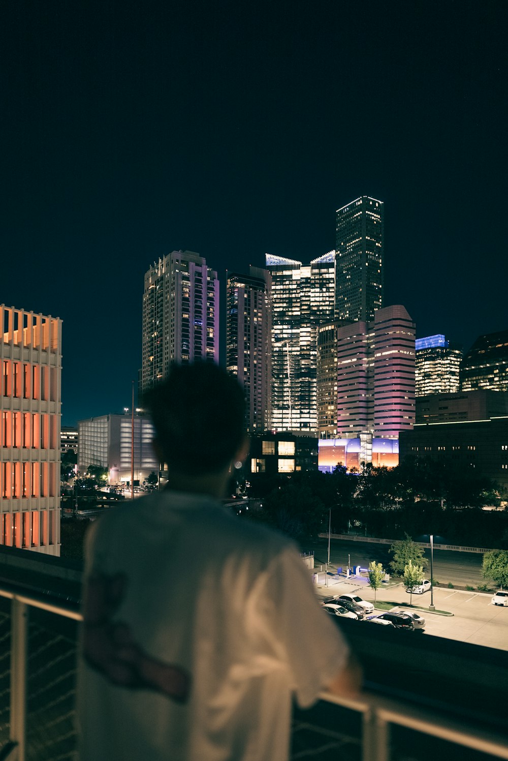 a man standing on a balcony overlooking a city at night